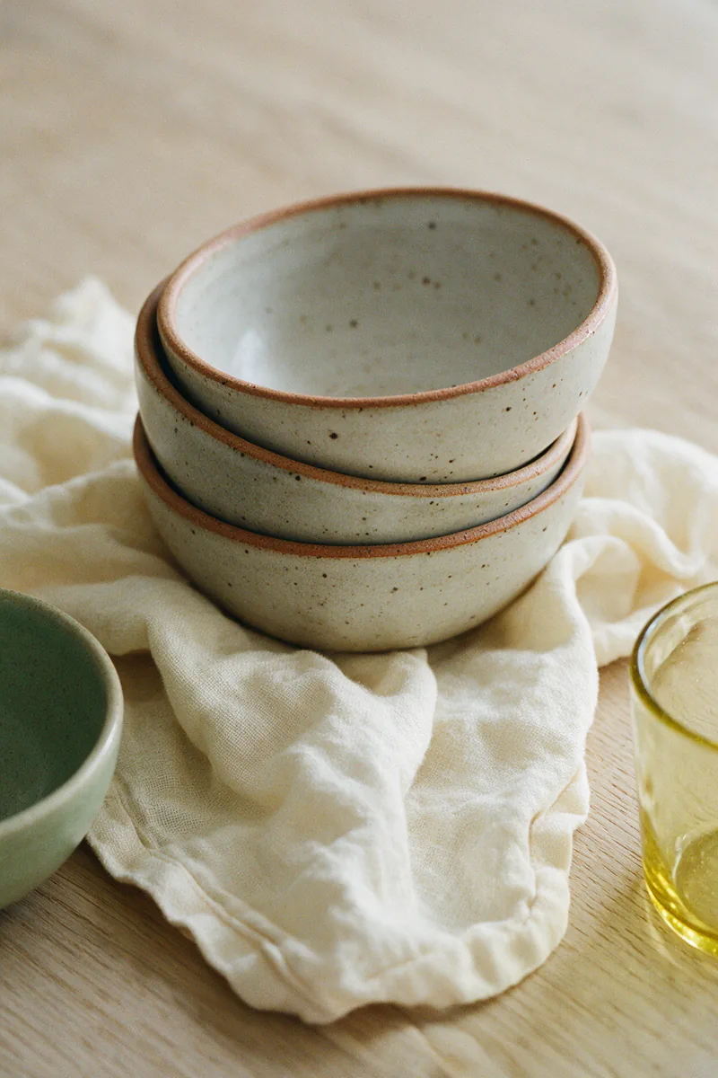 Speckled stoneware bowls with a matte glaze and raw clay rims.