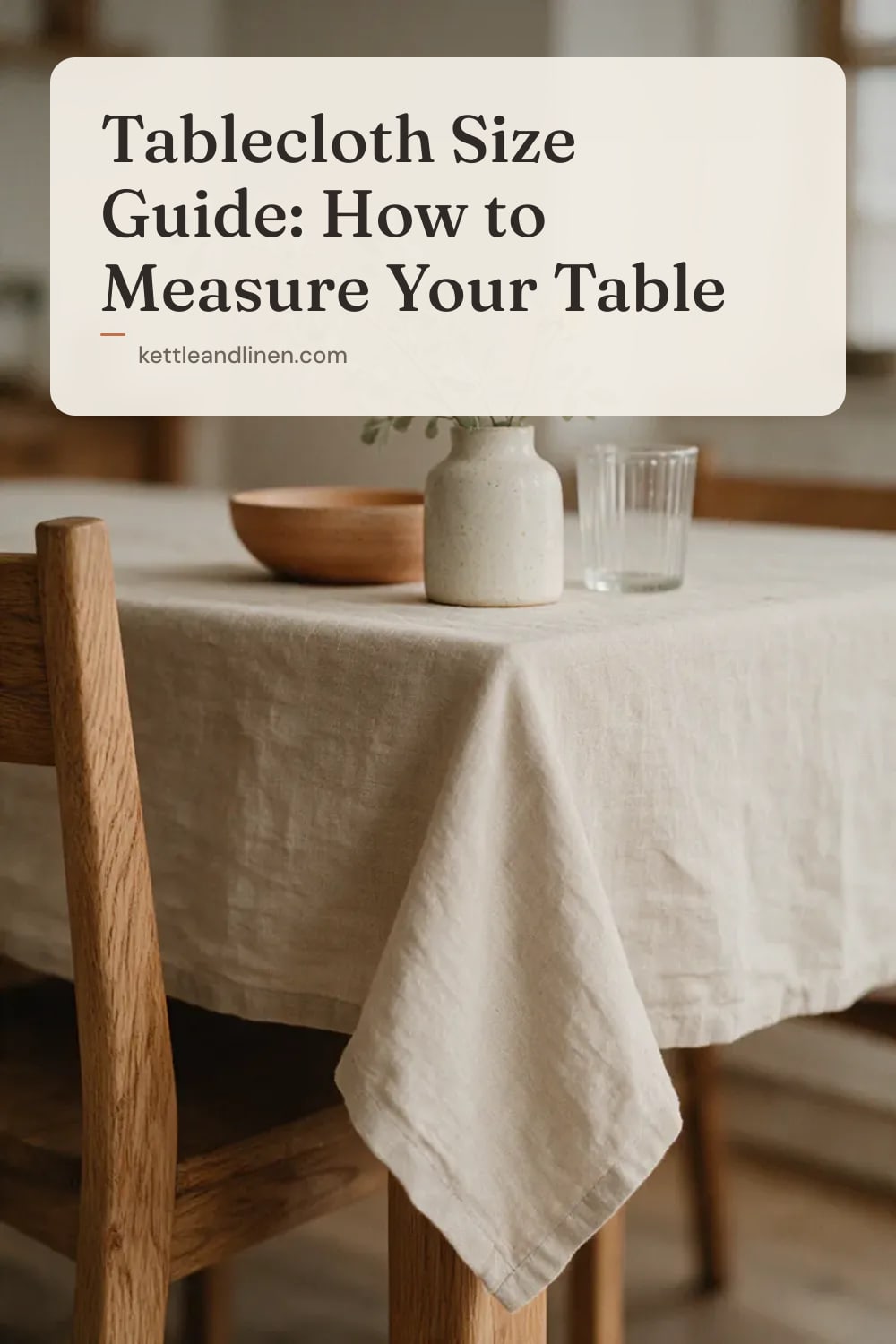 The corner of a dining table with an oat linen tablecloth hanging with a soft drop.